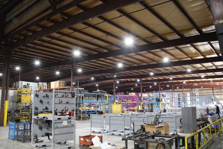 Wide view of a manufacturing shop floor with rows steel racks staged under high-bay lighting