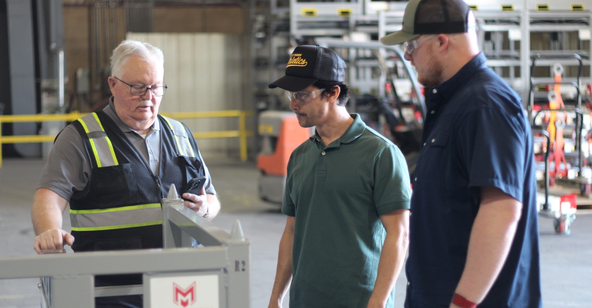 Three team members in discussion next to a steel rack on the shop floor