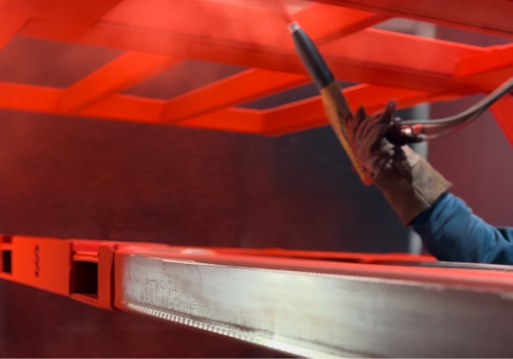 Custom metal component receiving a durable red powder coat finish on the in-house finishing line.