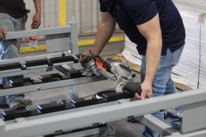 Worker using a tool on a gray steel rack on the shop floor