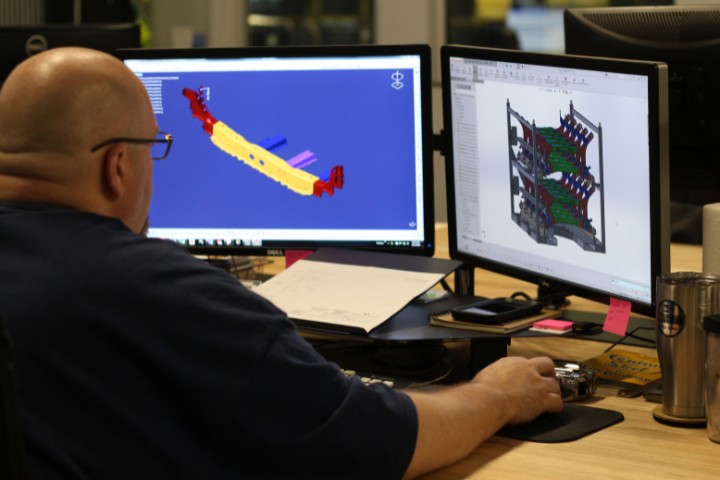 Engineer reviewing CAD models on dual monitors