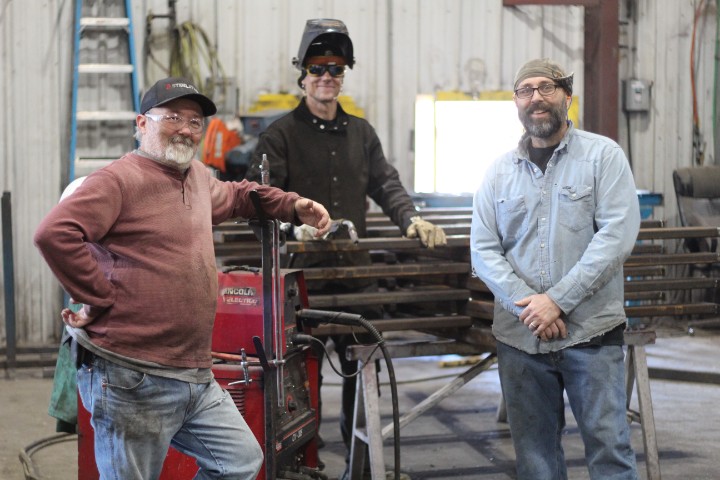 Three Morrison Industries employees collaborating on the shop floor of the Tennessee metal manufacturing facility.