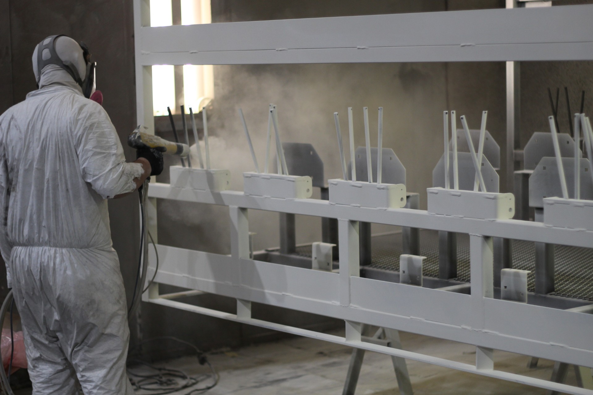 Custom steel parts hanging on the powder coating line after white finish application and cure.